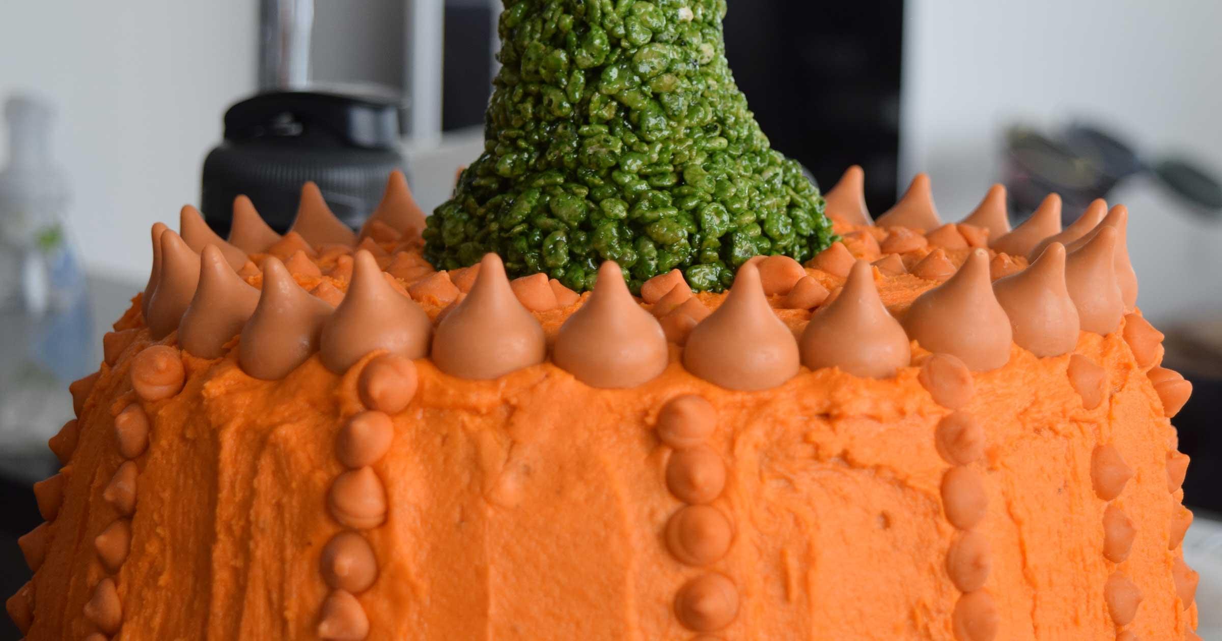 Close-up of the top of an orange pumpkin cake with a green stem made from rice cereal.