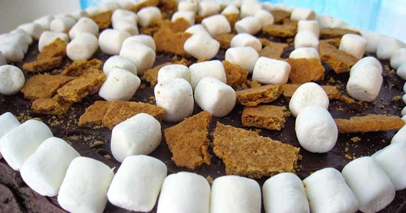Top of a cake covered with chocolate, mini marshmallows, and graham crackers.